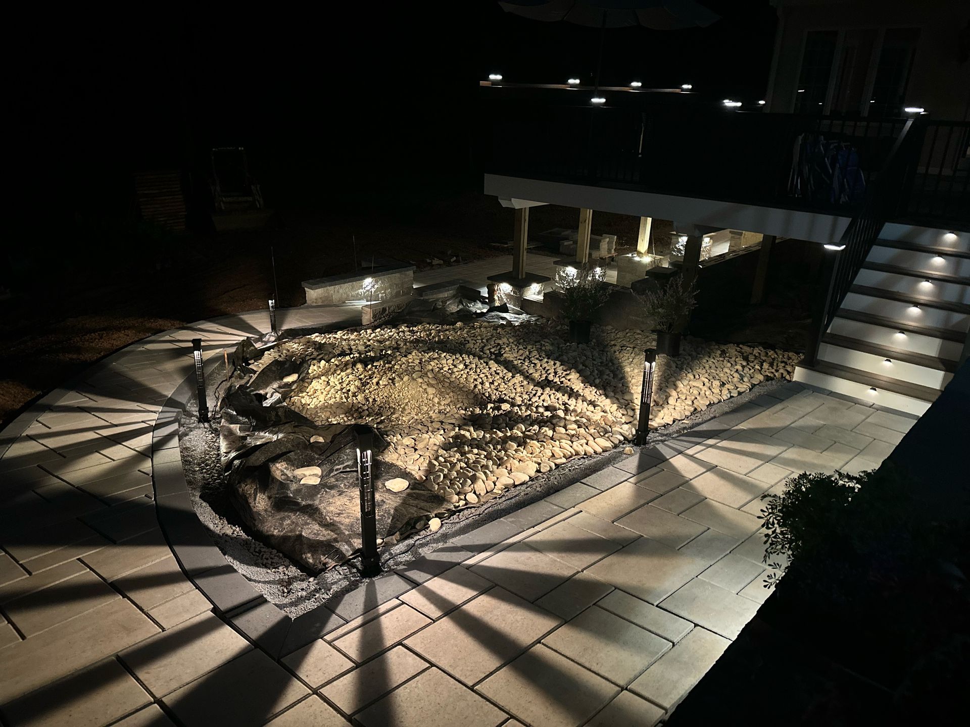 Dimly lit courtyard with a small landscaped island, tiled paths, and stairs with railings at night