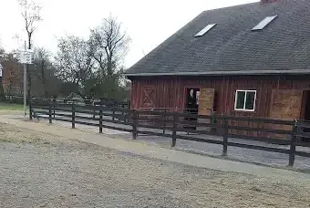 Red barn with dark wooden fence and gravel path.
