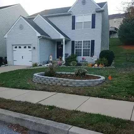 Two-story house with gray siding, a small garden bed in front, and a sidewalk.