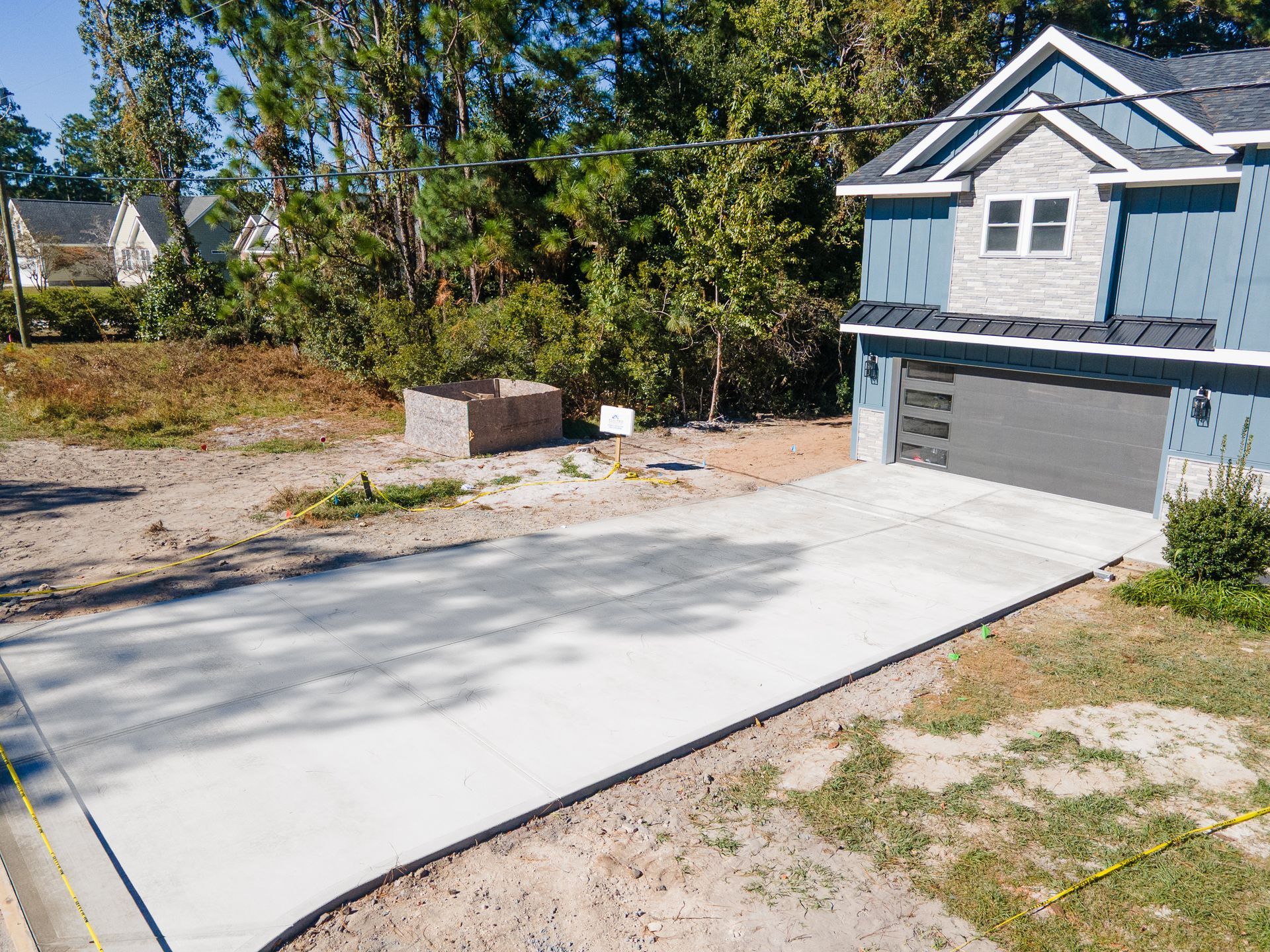 New concrete driveway leading to a gray two-story house with a garage