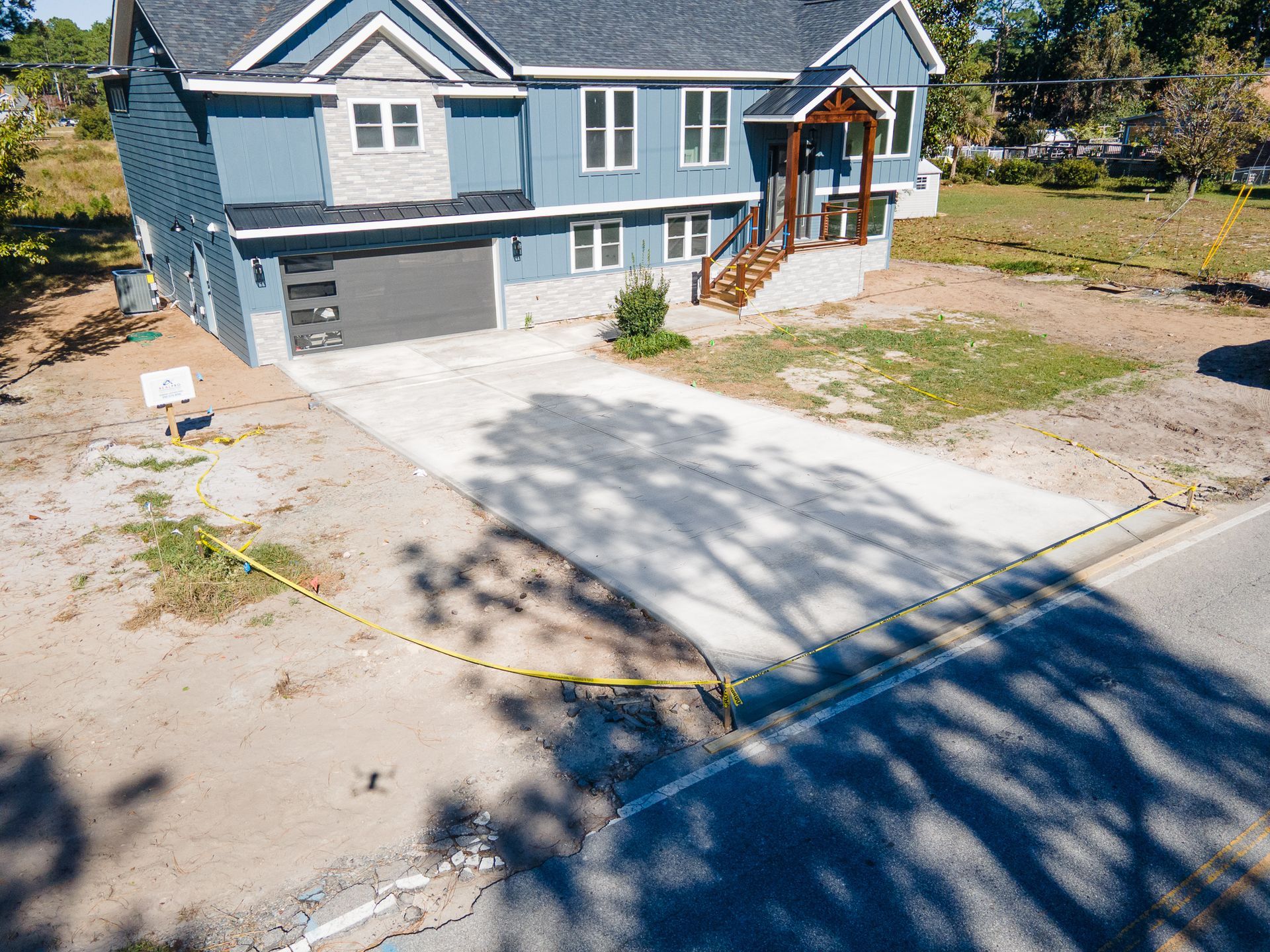 Blue two-story house with white trim, front porch, and driveway in a suburban neighborhood