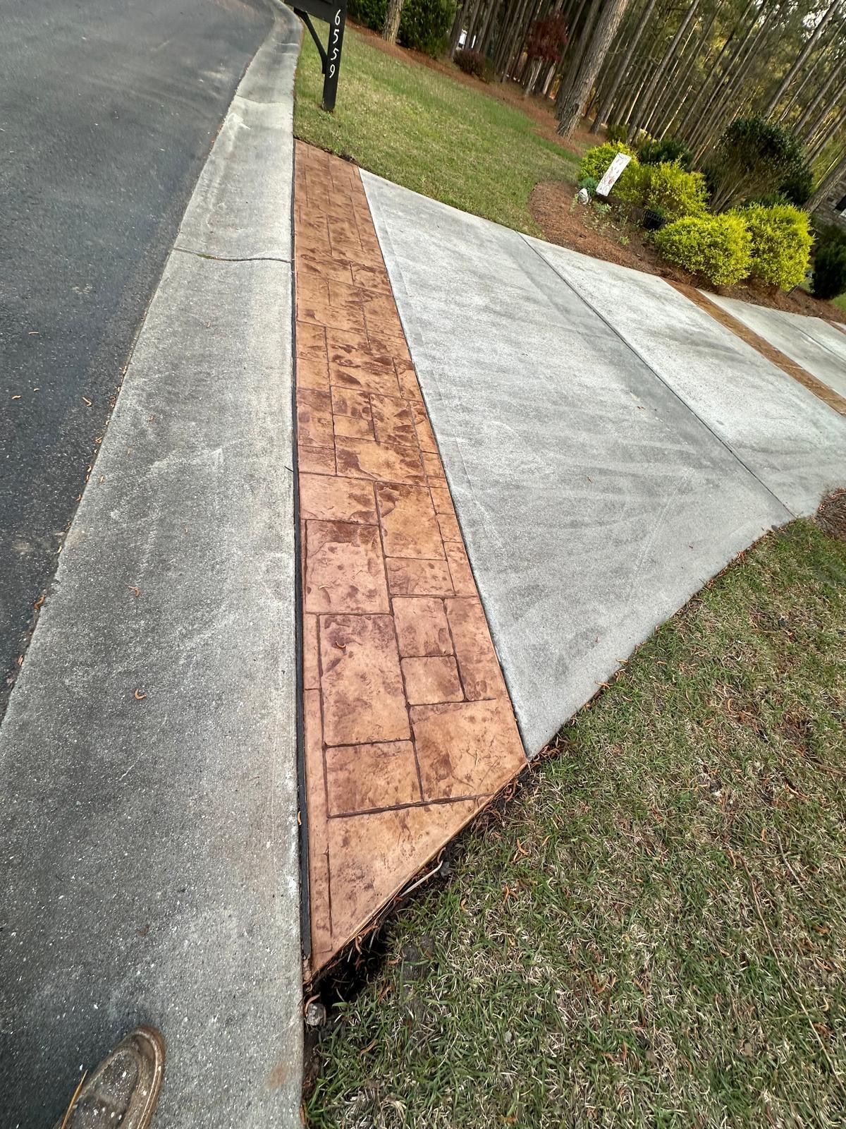Diagonal brick strip between driveway and sidewalk beside grass and bushes