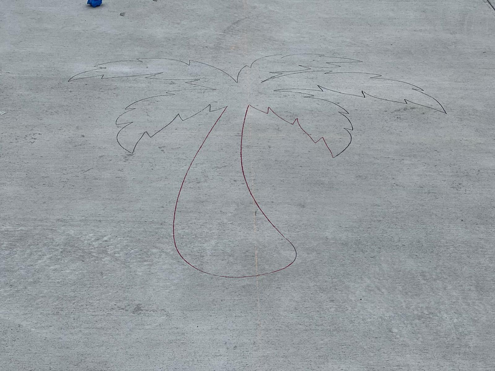 A faint chalk drawing of a face with wavy hair on a gray concrete surface.