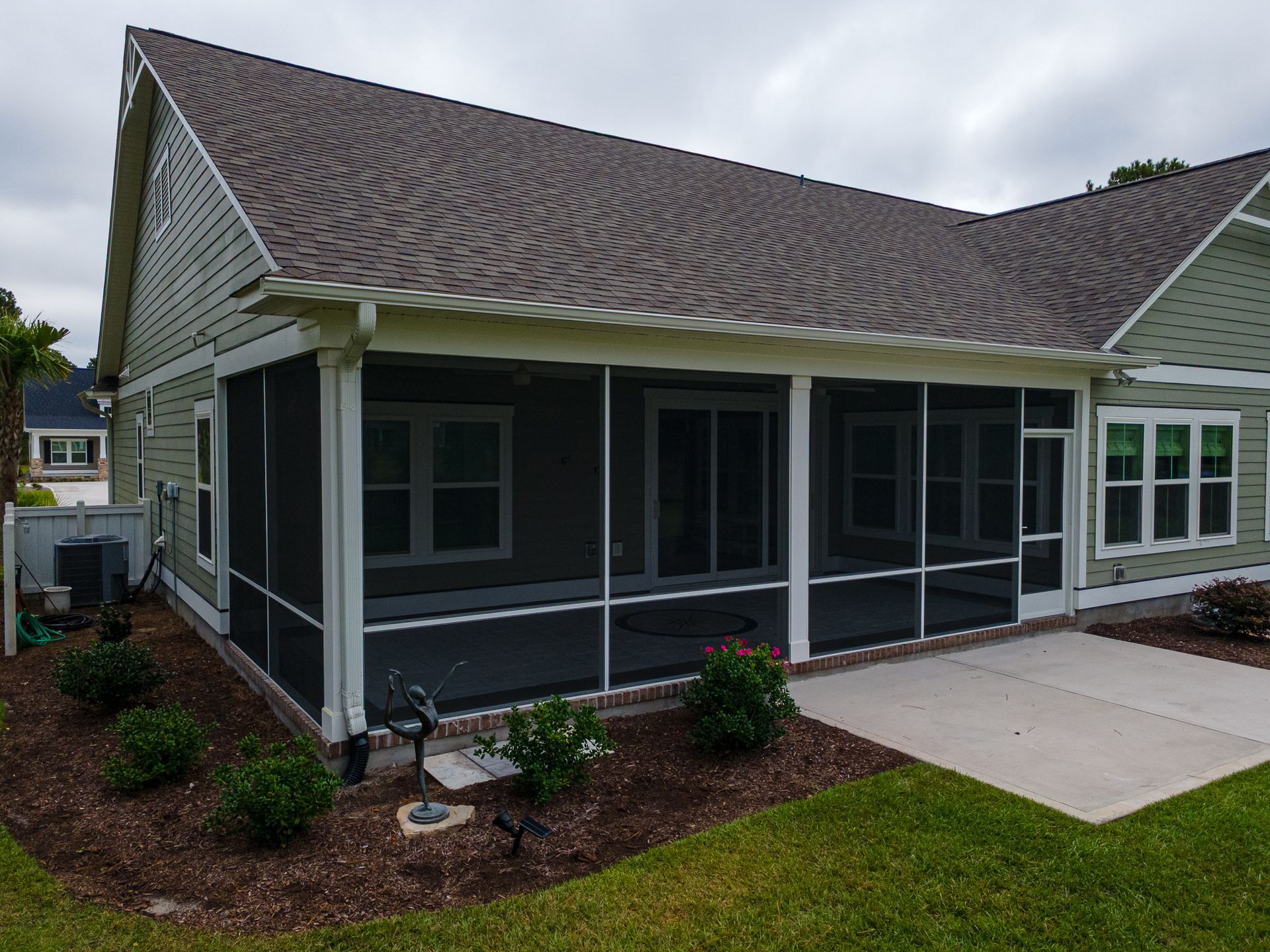Single-story house with screened porch, gray siding, and landscaped front yard
