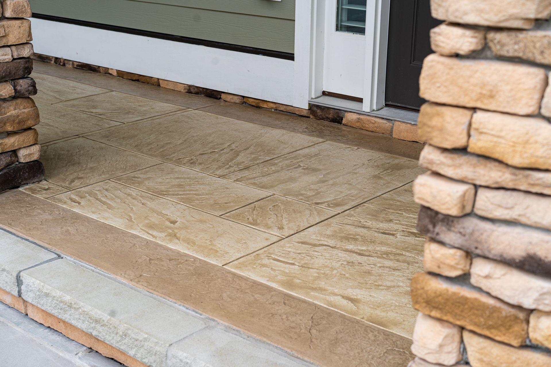 Stone-front porch with concrete steps and a front door entrance