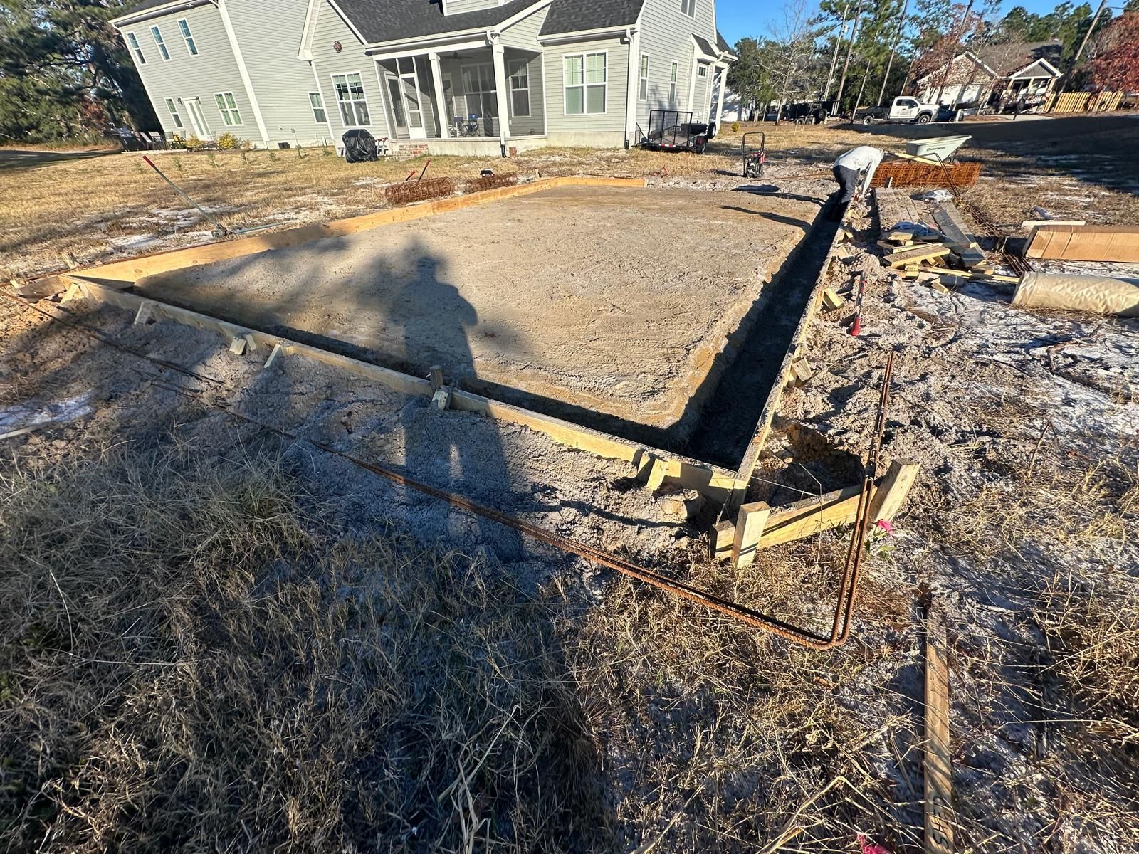 Residential construction site with concrete foundation slab and wooden forms in a yard