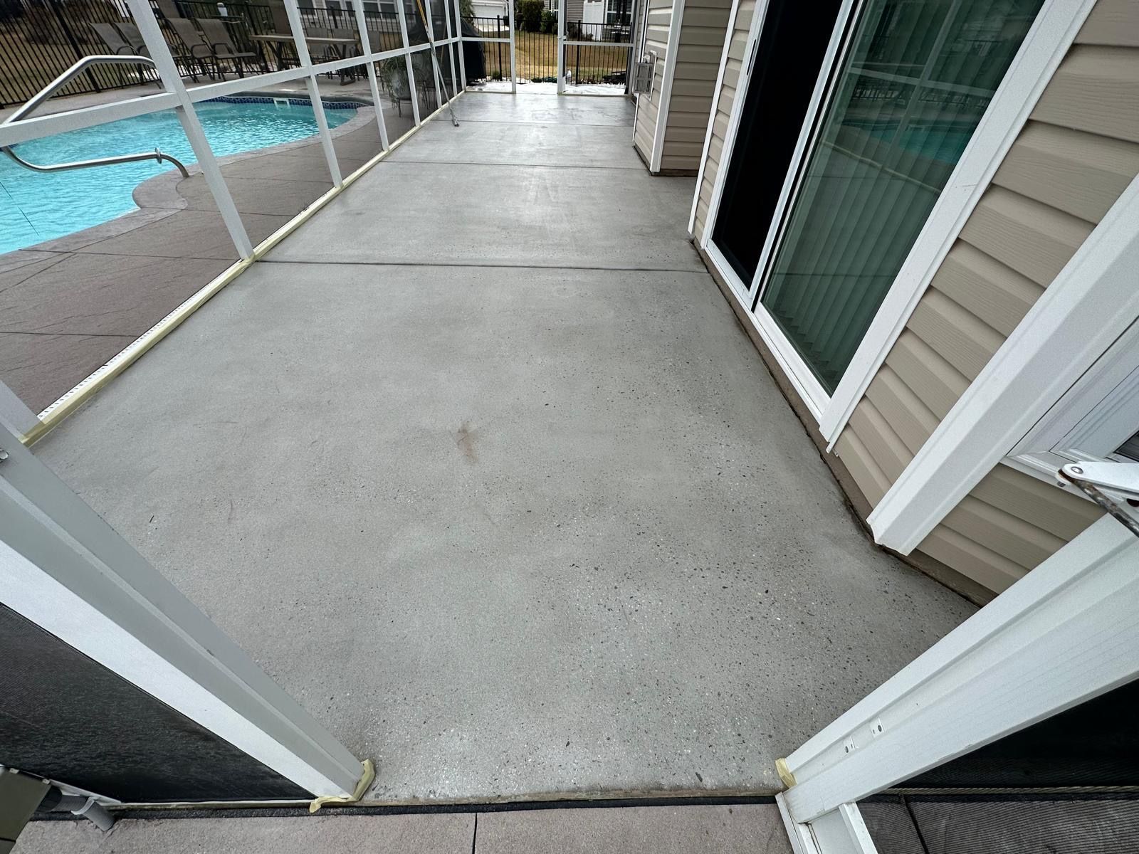 Narrow concrete balcony walkway beside a pool, with sliding glass doors and apartment siding on the right.