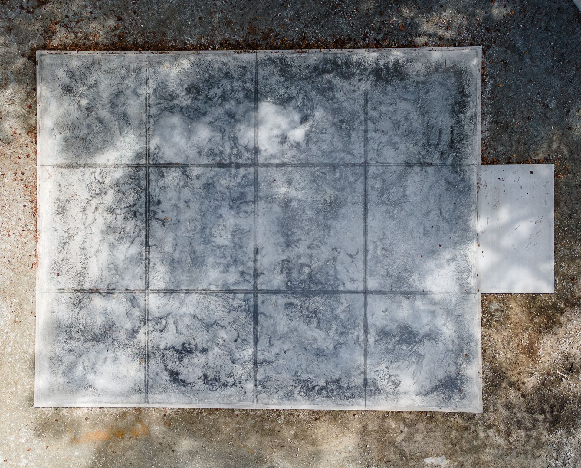 Weathered concrete slab with faint grid lines and a small white protruding panel on the right.