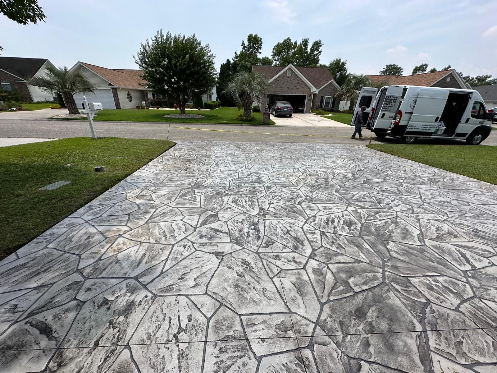 Stamped concrete driveway with a white van parked on the right in a suburban neighborhood