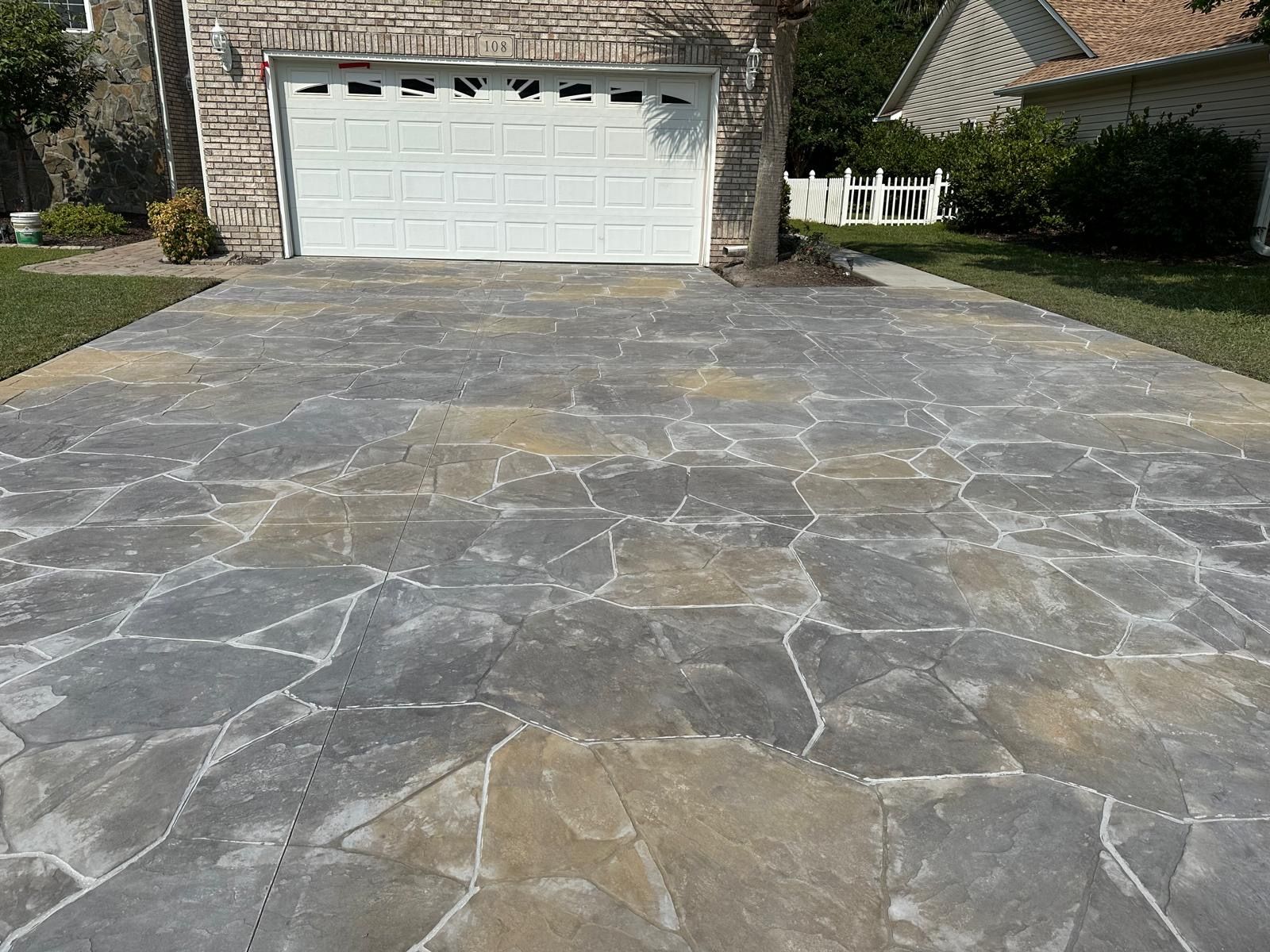 Stone driveway leading to a white garage door in a suburban home