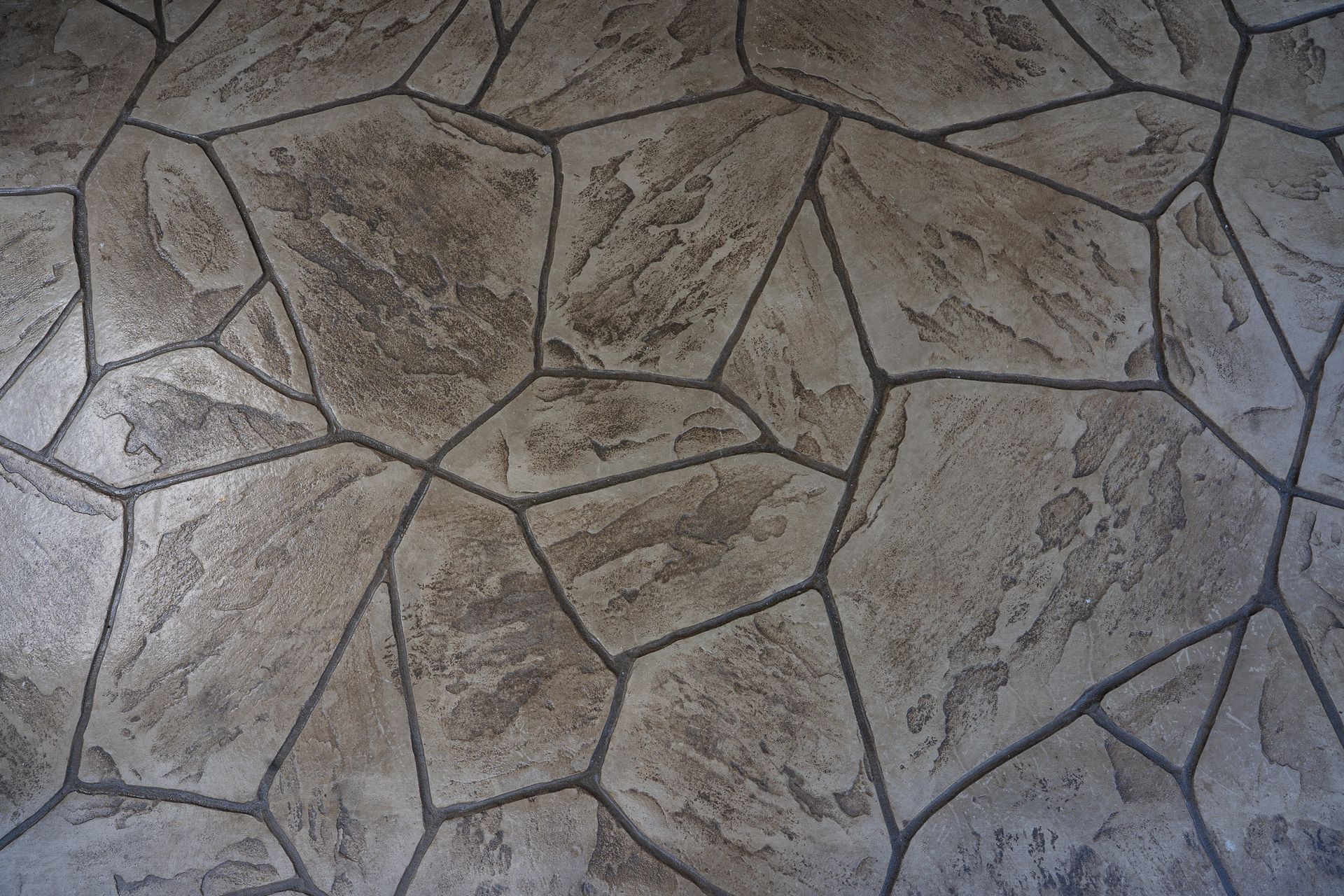 Close-up of a gray stone-patterned textured surface with irregular grout lines