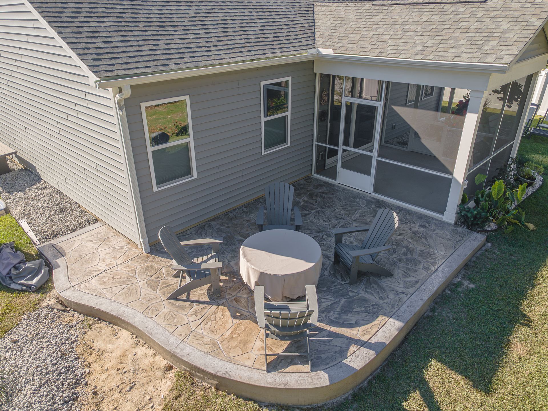 Patio with round table, chairs, and stone seating beside a house with a covered porch