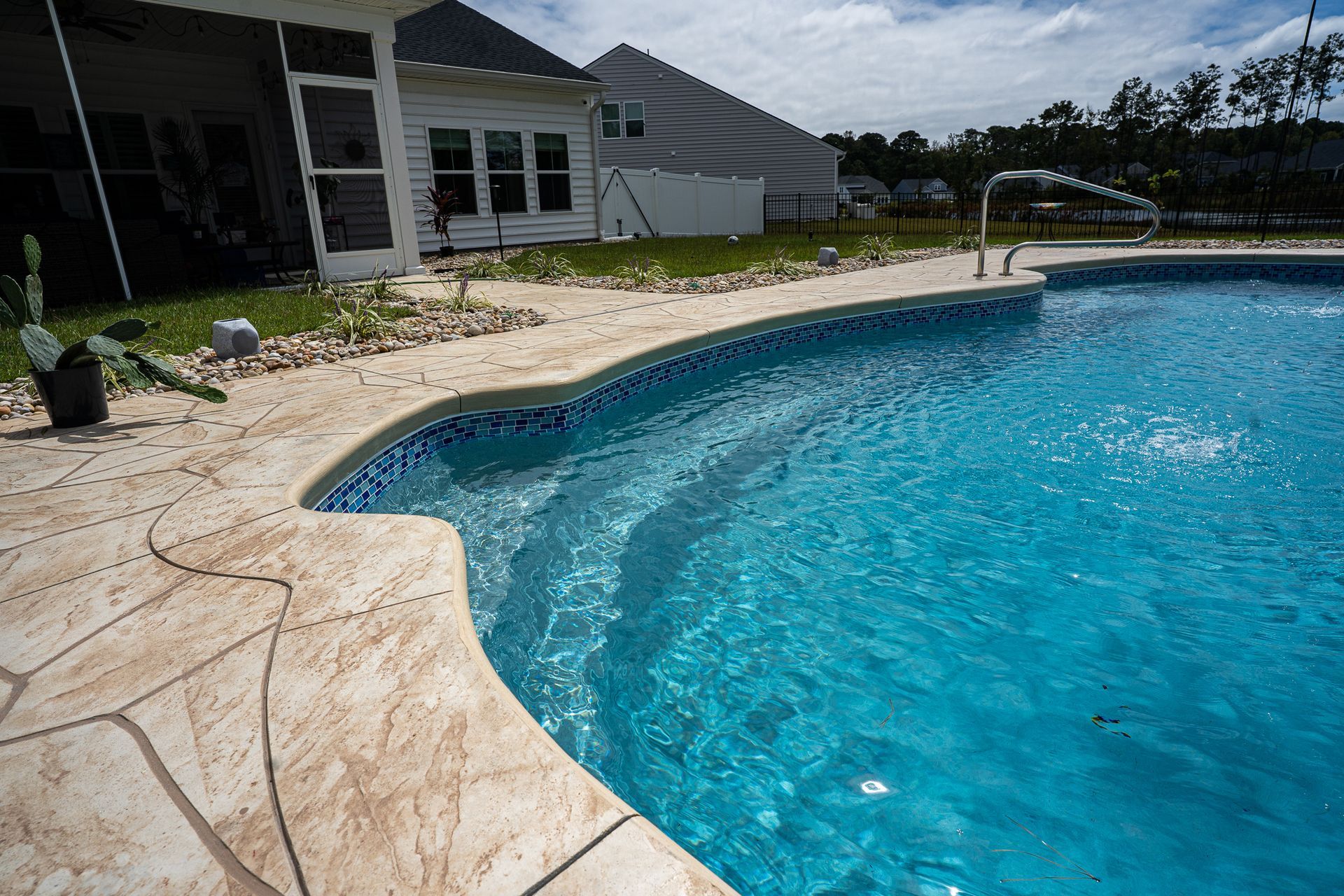 Backyard swimming pool with blue water beside a patio and house