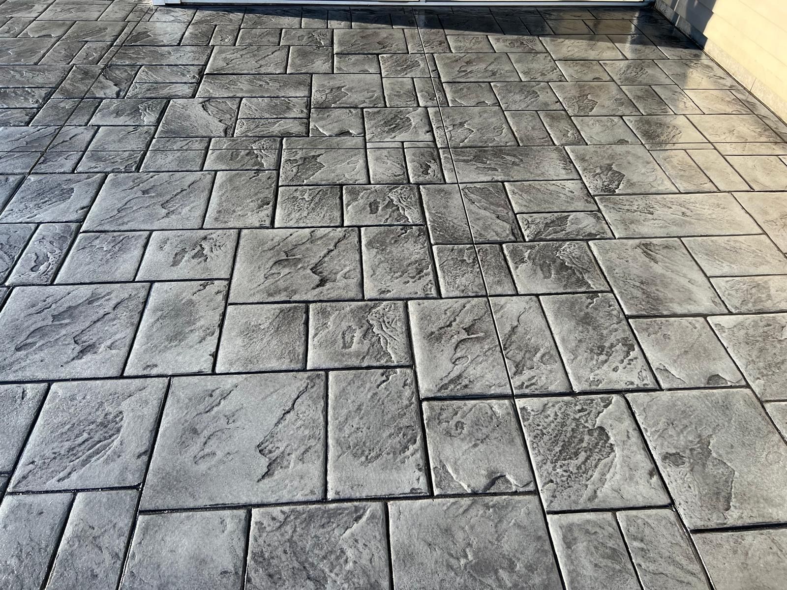 Gray stone patio pavers with a rectangular patterned surface in outdoor light