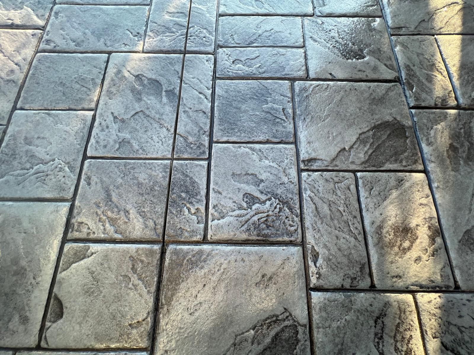 Stone-paved walkway with irregular gray tiles and sunlight shadows