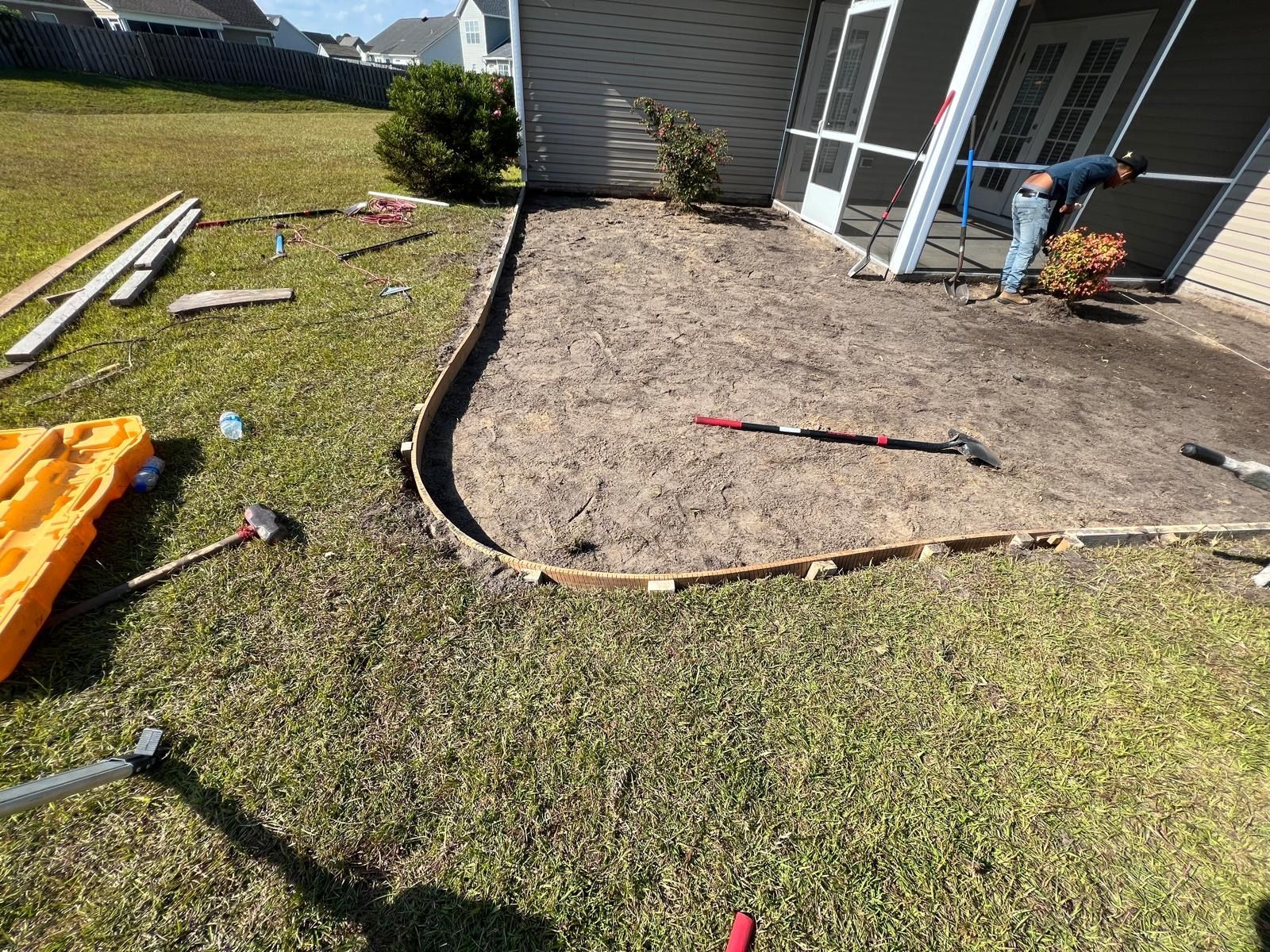 Backyard patio with fresh gravel and edging beside a grassy lawn and house porch