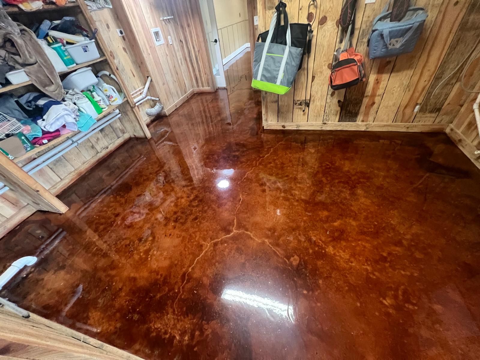 Shiny varnished wooden floor in a rustic room with tools and storage shelves along the walls