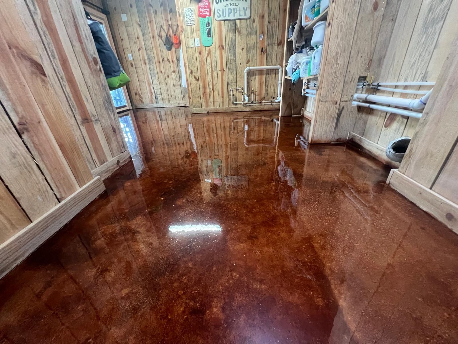 Rustic wooden room with a glossy flooded floor reflecting light and doorways.