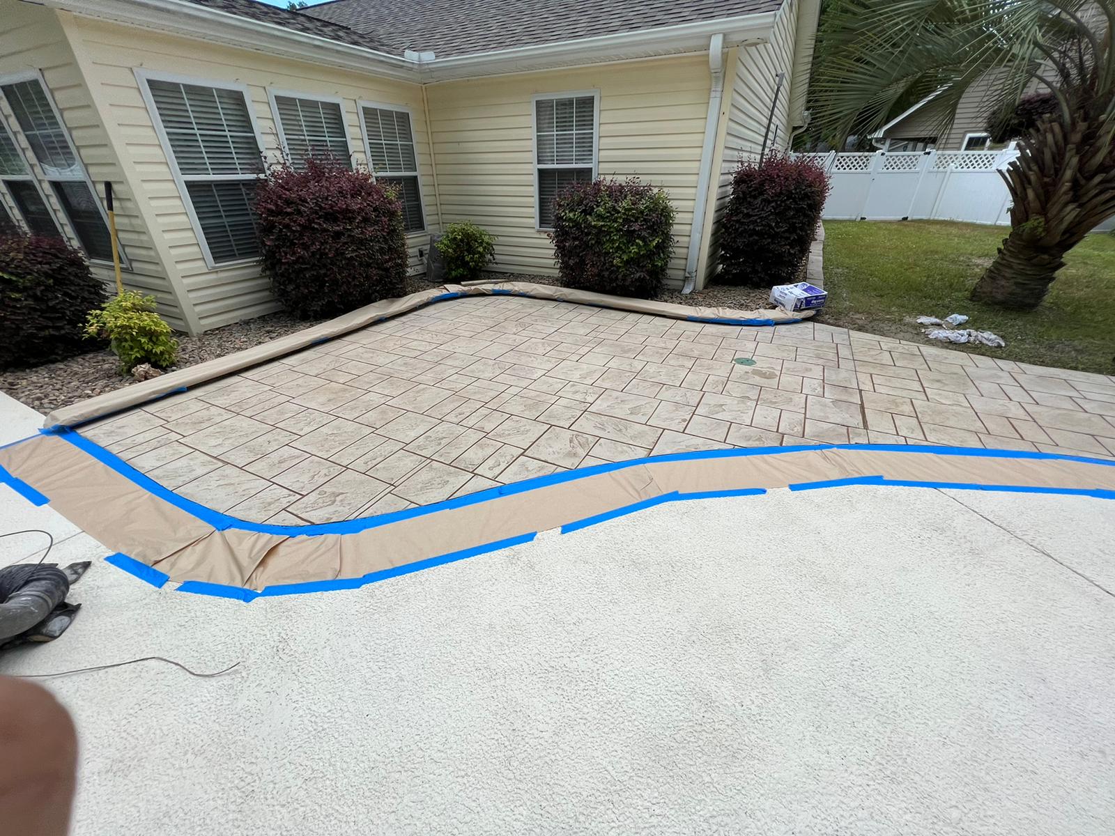 A brick driveway is being painted in front of a house.