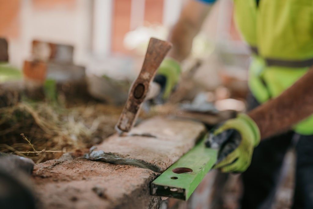 Worker leveling wet concrete with a trowel and green float at a construction site