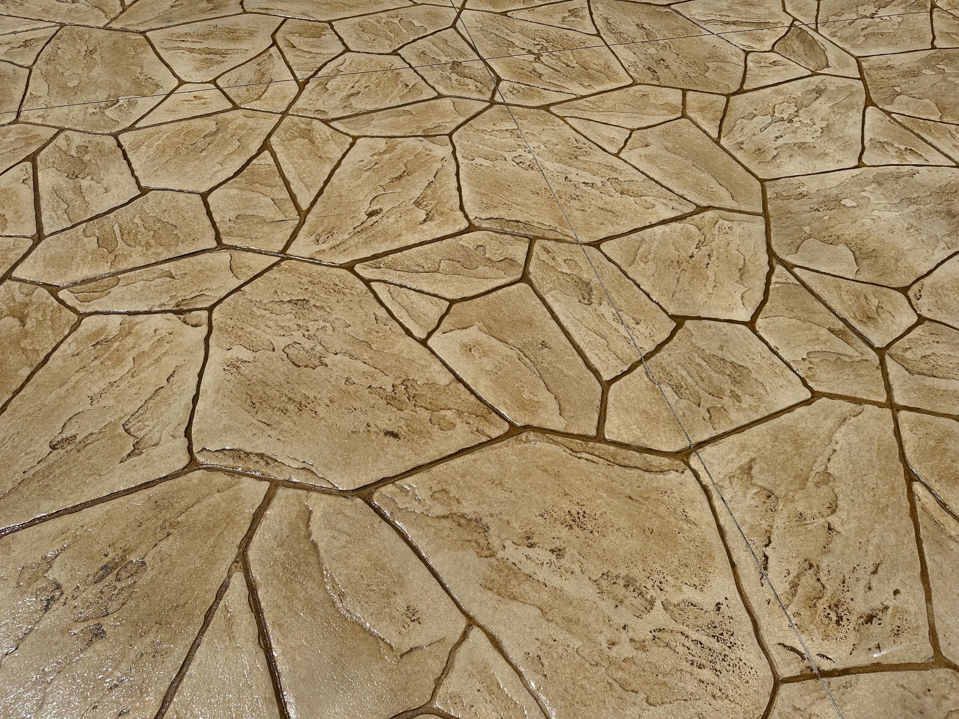 Cracked tan stone pavement with irregular polygon tiles