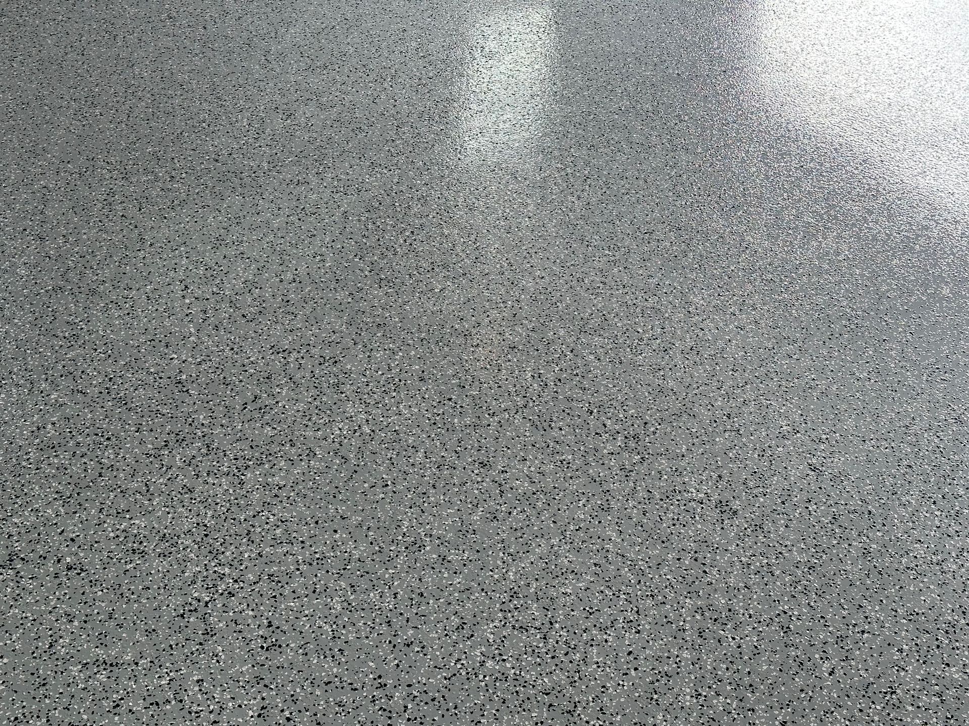 Close-up of a gray speckled surface with a bright reflection near the top.