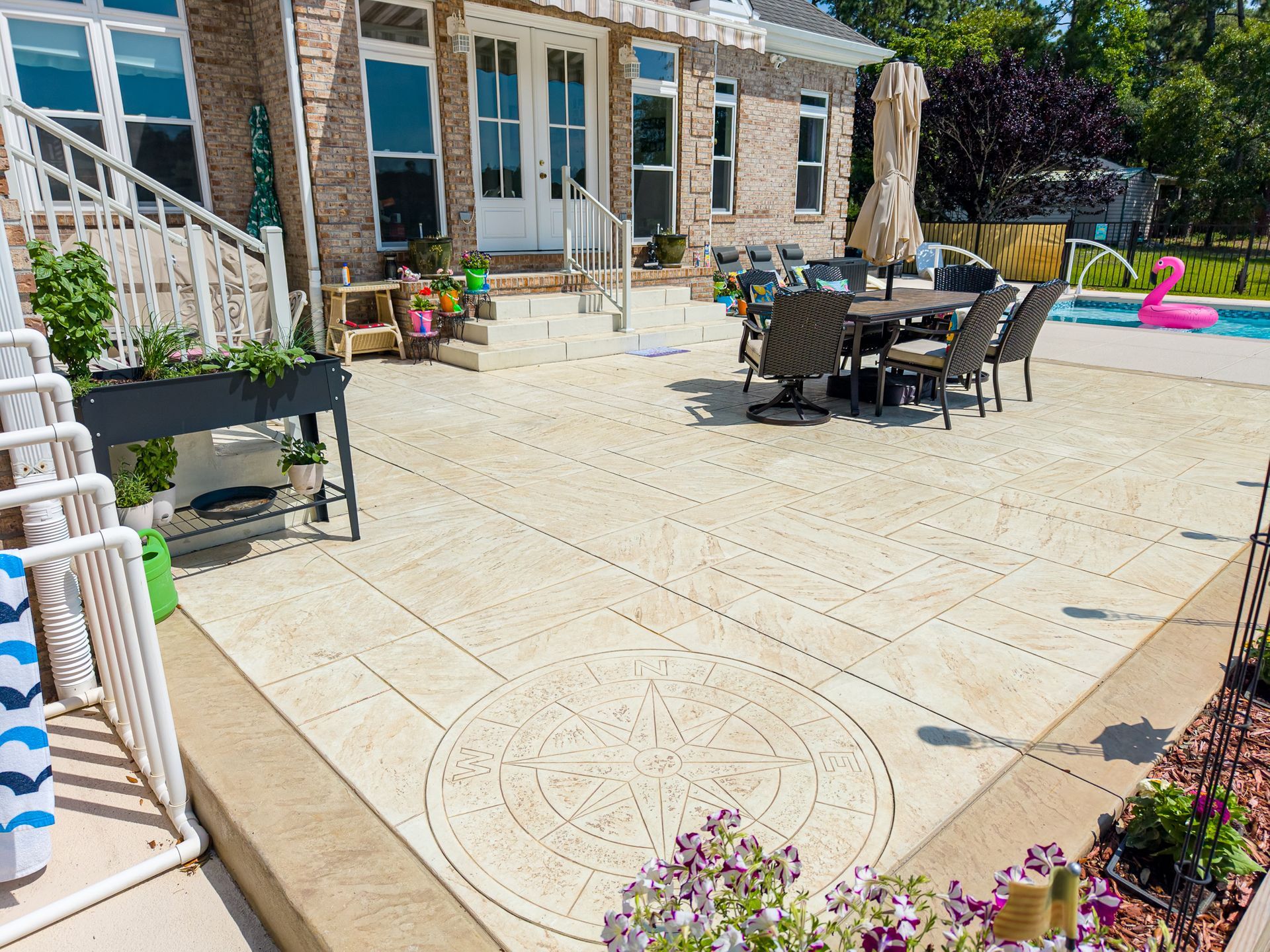 Backyard patio with stone house, outdoor dining table, and colorful pool float by a swimming pool.