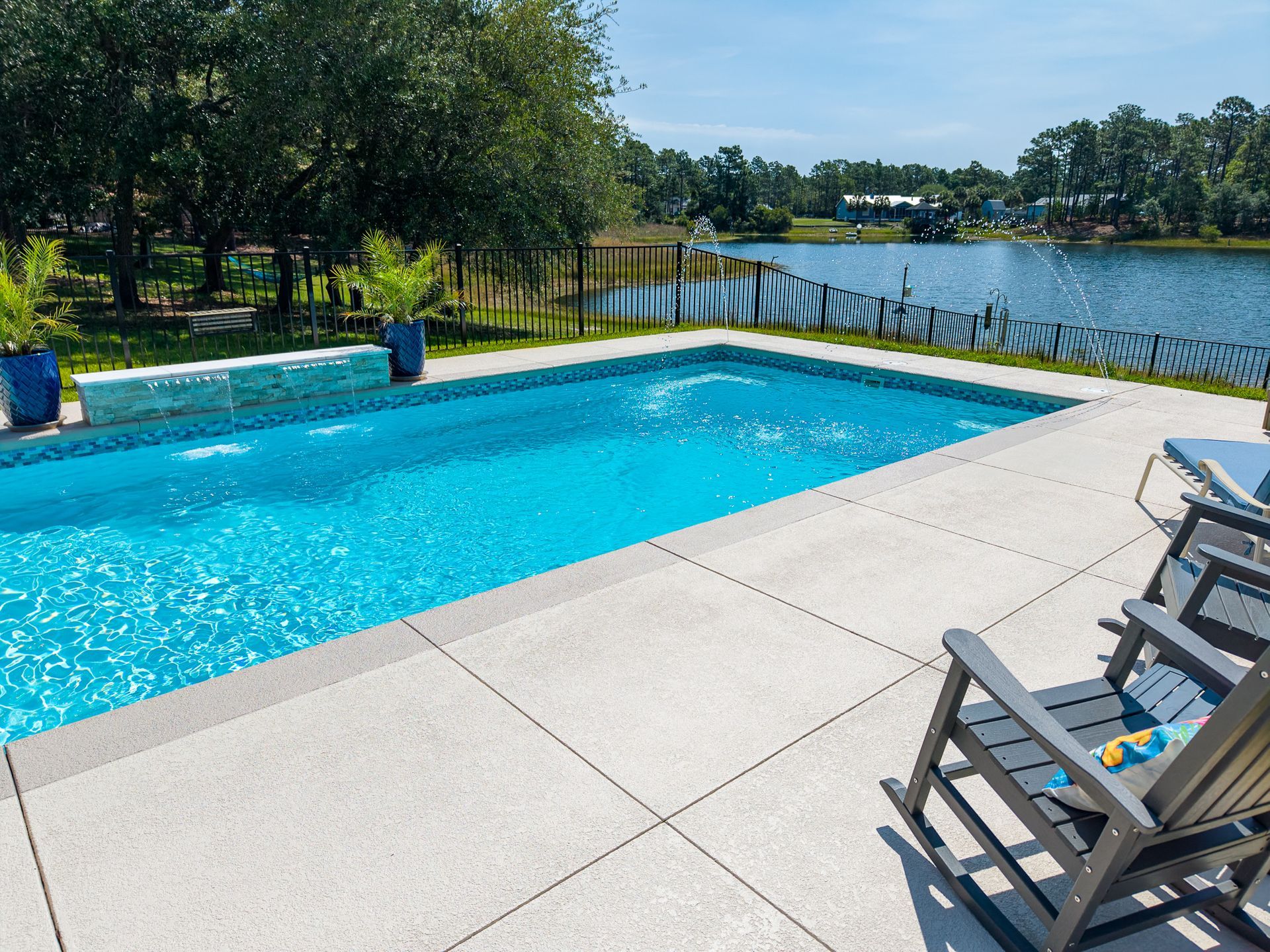 Backyard pool beside a lake, with lounge chairs and a sunny blue sky