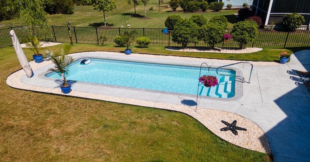Backyard swimming pool with blue water, lounge chairs, and a lawn in the foreground