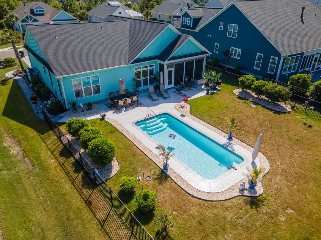 Aerial view of a turquoise house with a backyard pool, patio, and lawn.