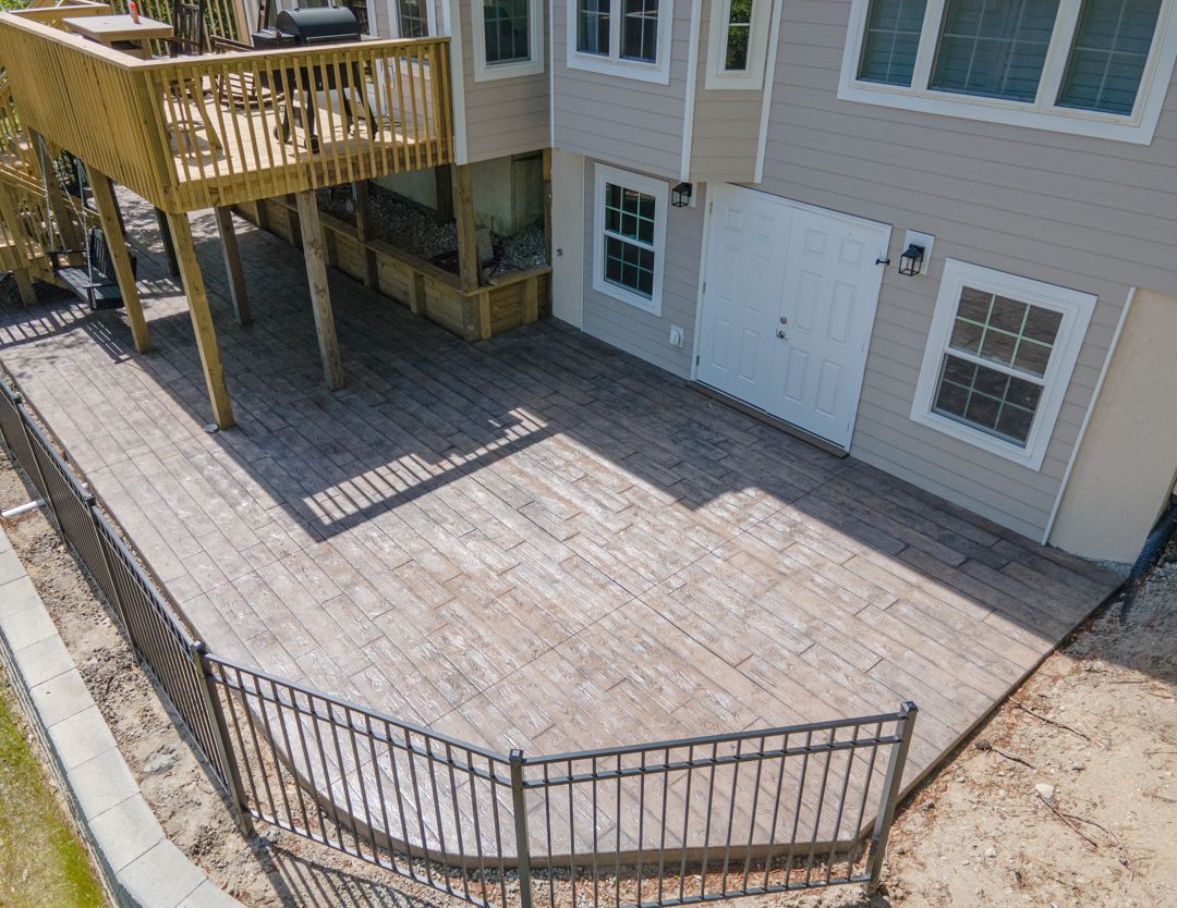 Backyard deck and patio with wooden fence gate beside a house exterior, viewed from above