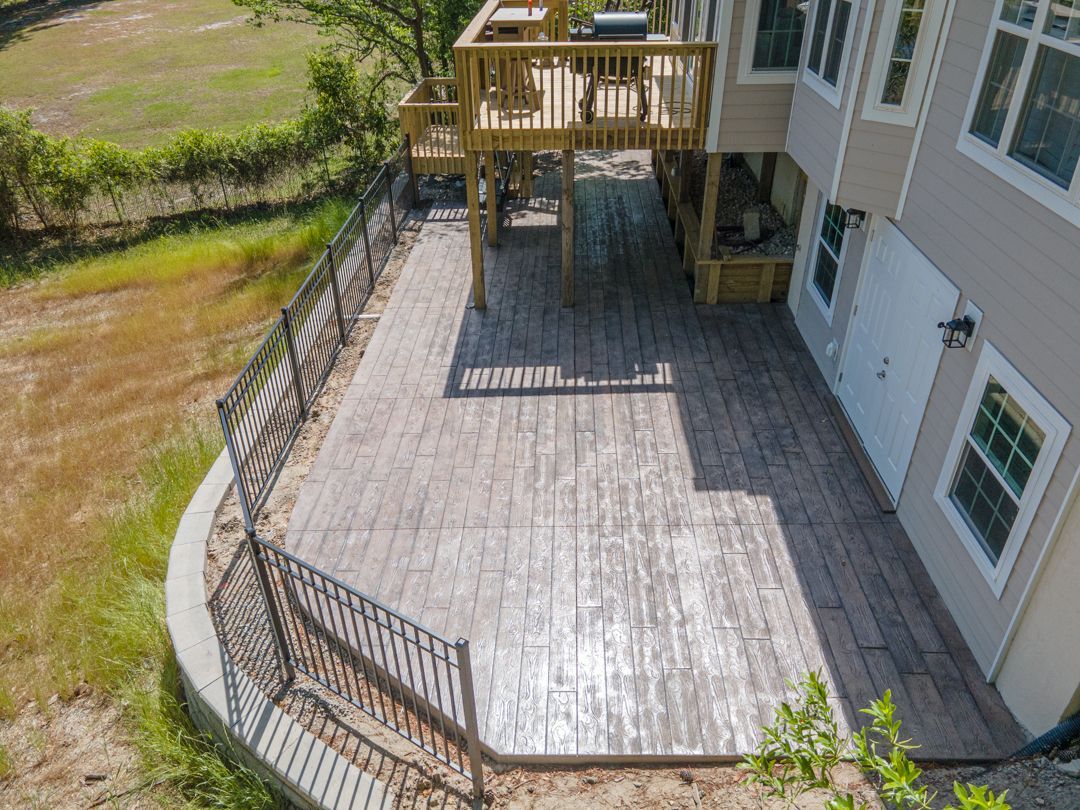 Wooden backyard deck with railings beside a house and grassy yard below