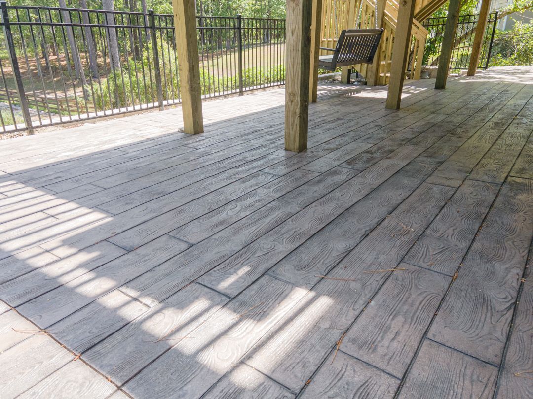 Wooden deck with railing, posts, and a bench, viewed in bright sunlight.