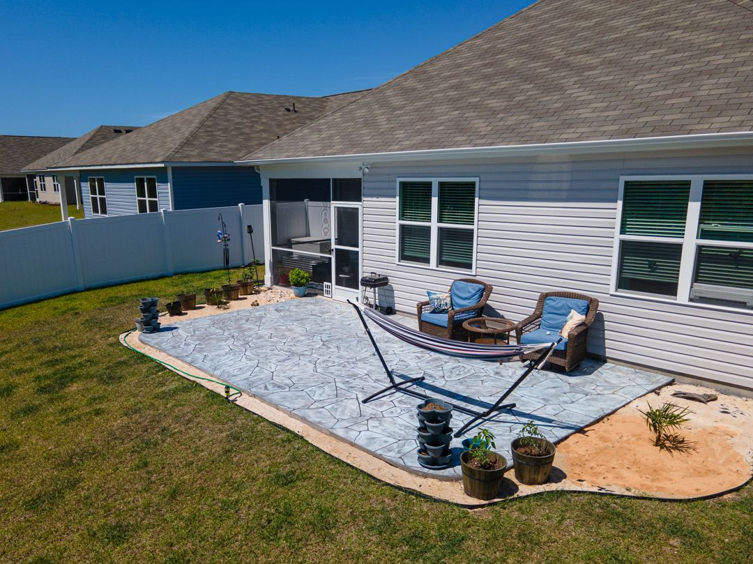 Back patio with blue outdoor furniture, gray pavers, hammock chair, and white house siding.