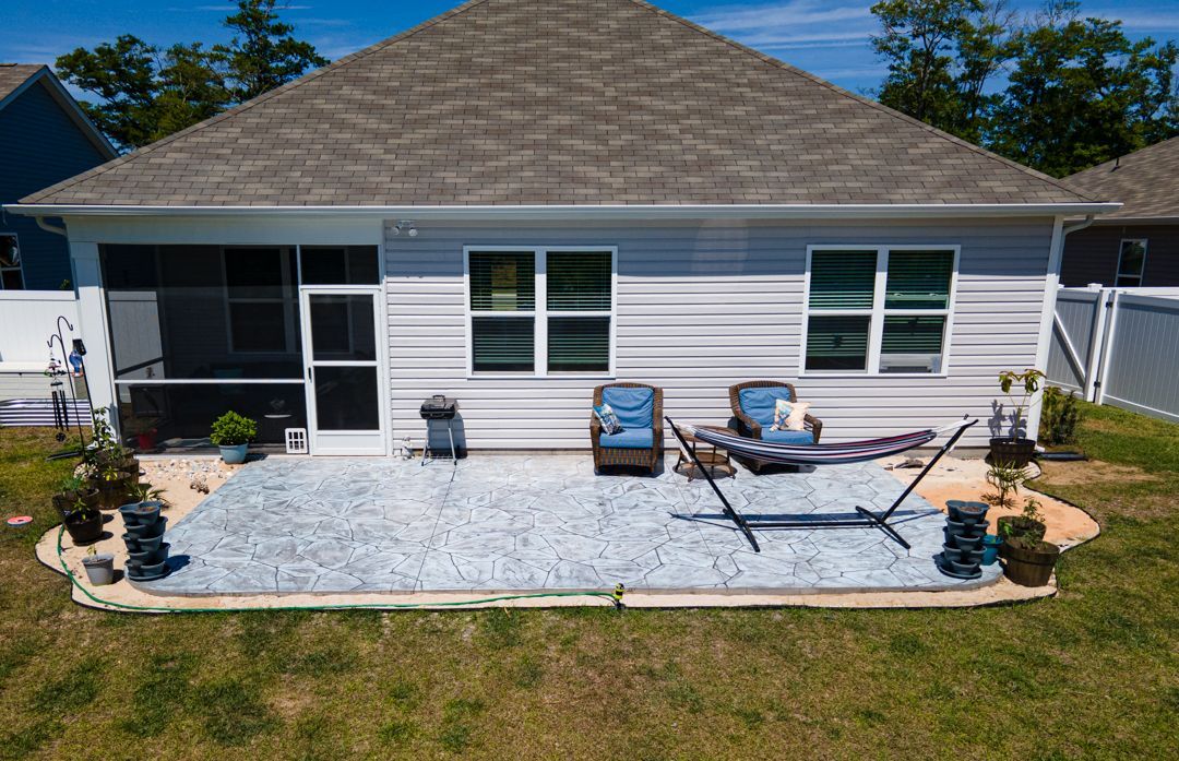 Backyard patio with lounge chairs and seating against a white house.