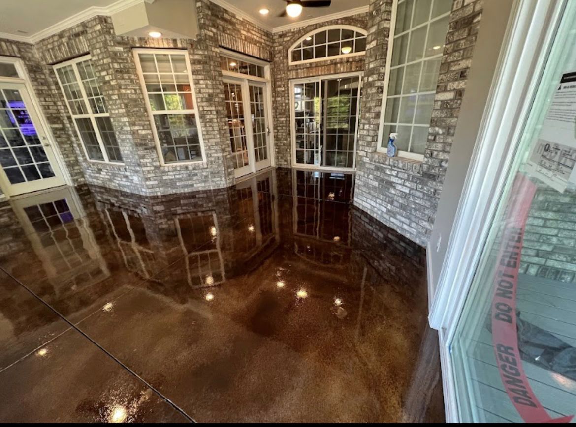Glossy dark wood floor in an empty sunroom with stone walls and white-trimmed windows