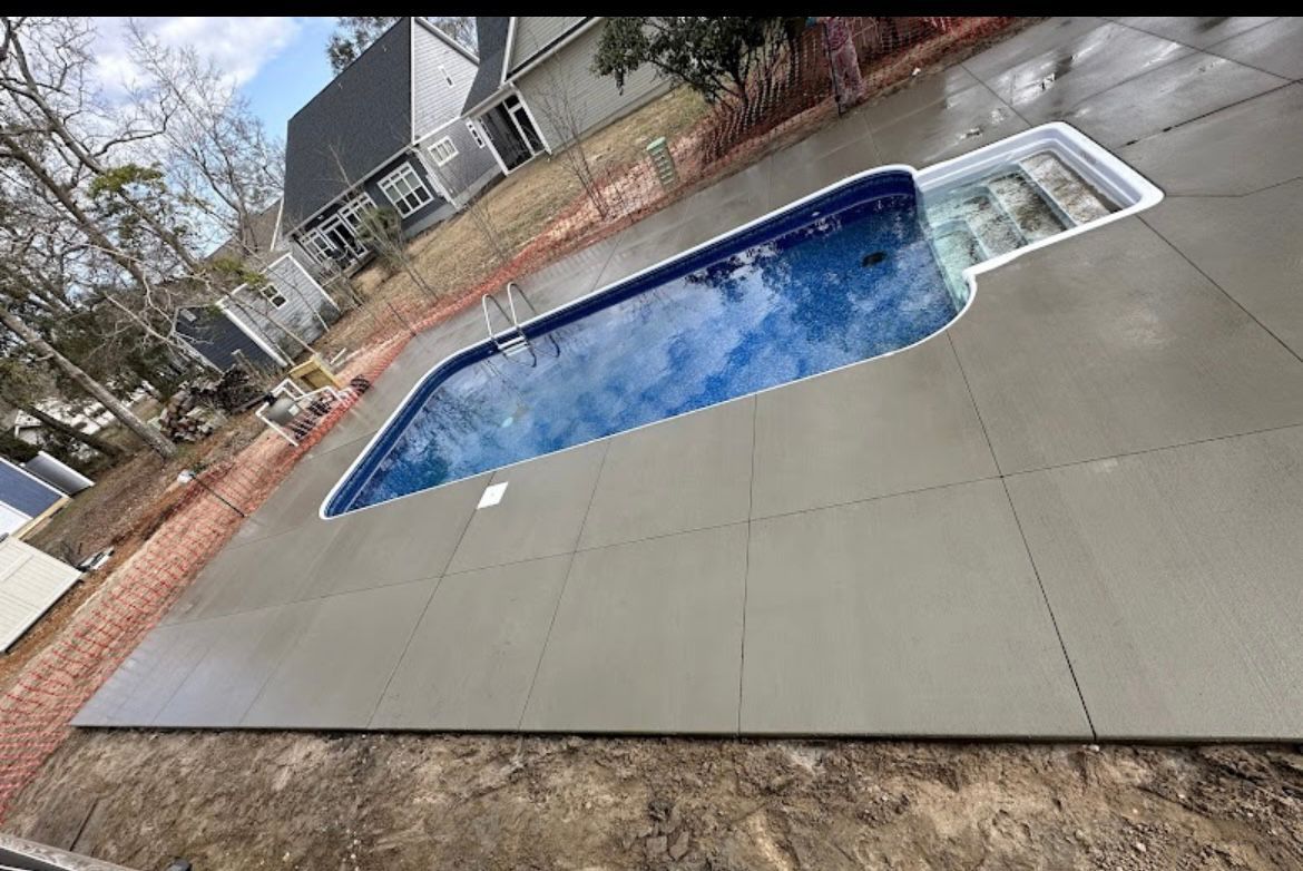 Backyard in-ground pool with blue water and a gray pool deck, viewed at an angle.