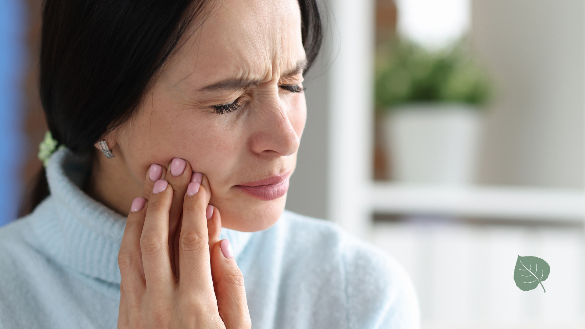 A woman is holding her face in pain because of a toothache.