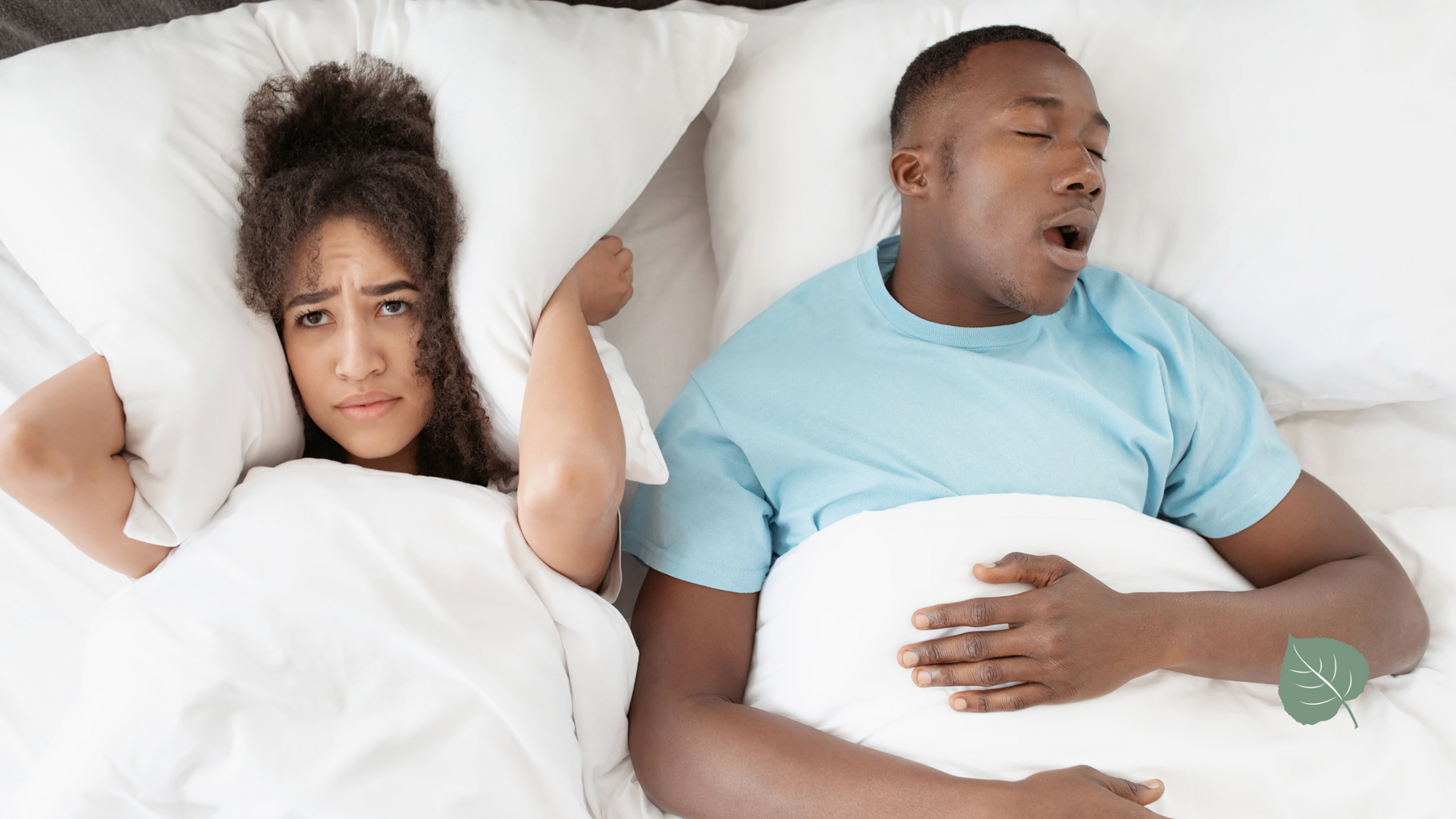 Woman covers ears with pillow; man snores in bed.
