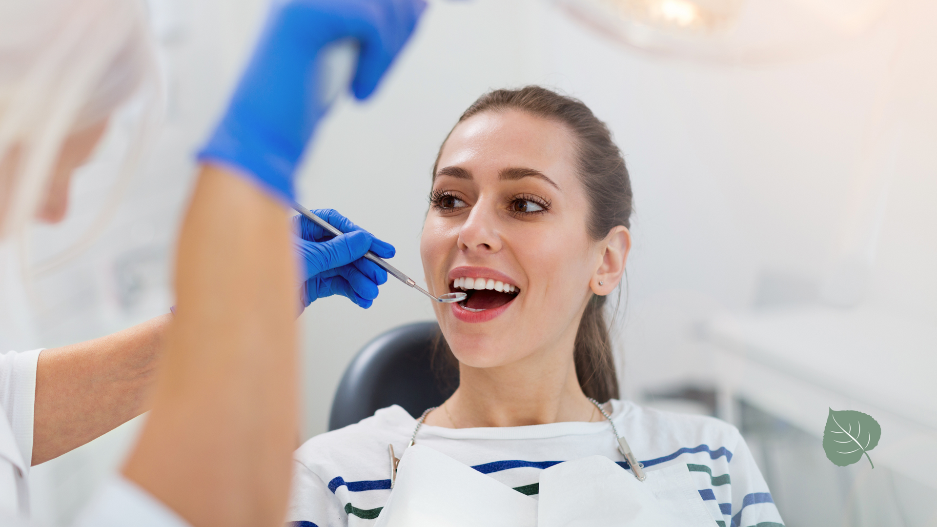 A woman is sitting in a dental chair getting her teeth examined by a dentist.