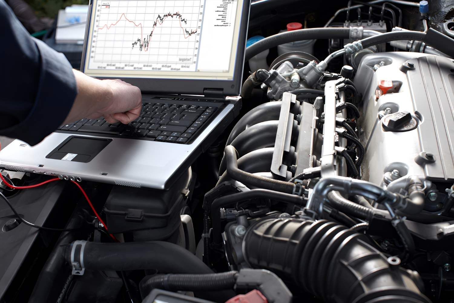 A Man is Working on a Car Engine With a Laptop — Fraser Mobile Auto Tech in Tolga, QLD