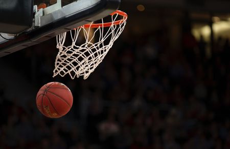 Uma bola de basquete está passando por um aro com uma multidão assistindo