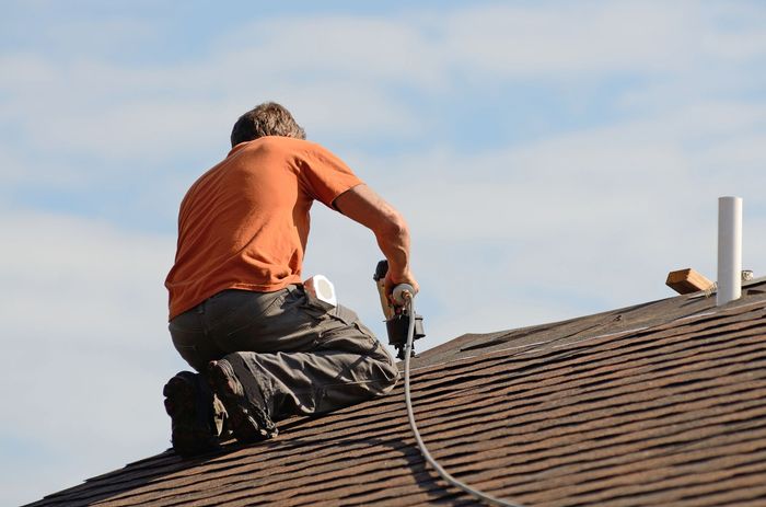 A roofing contractor is installing an asphalt roof on a residential home for durability.