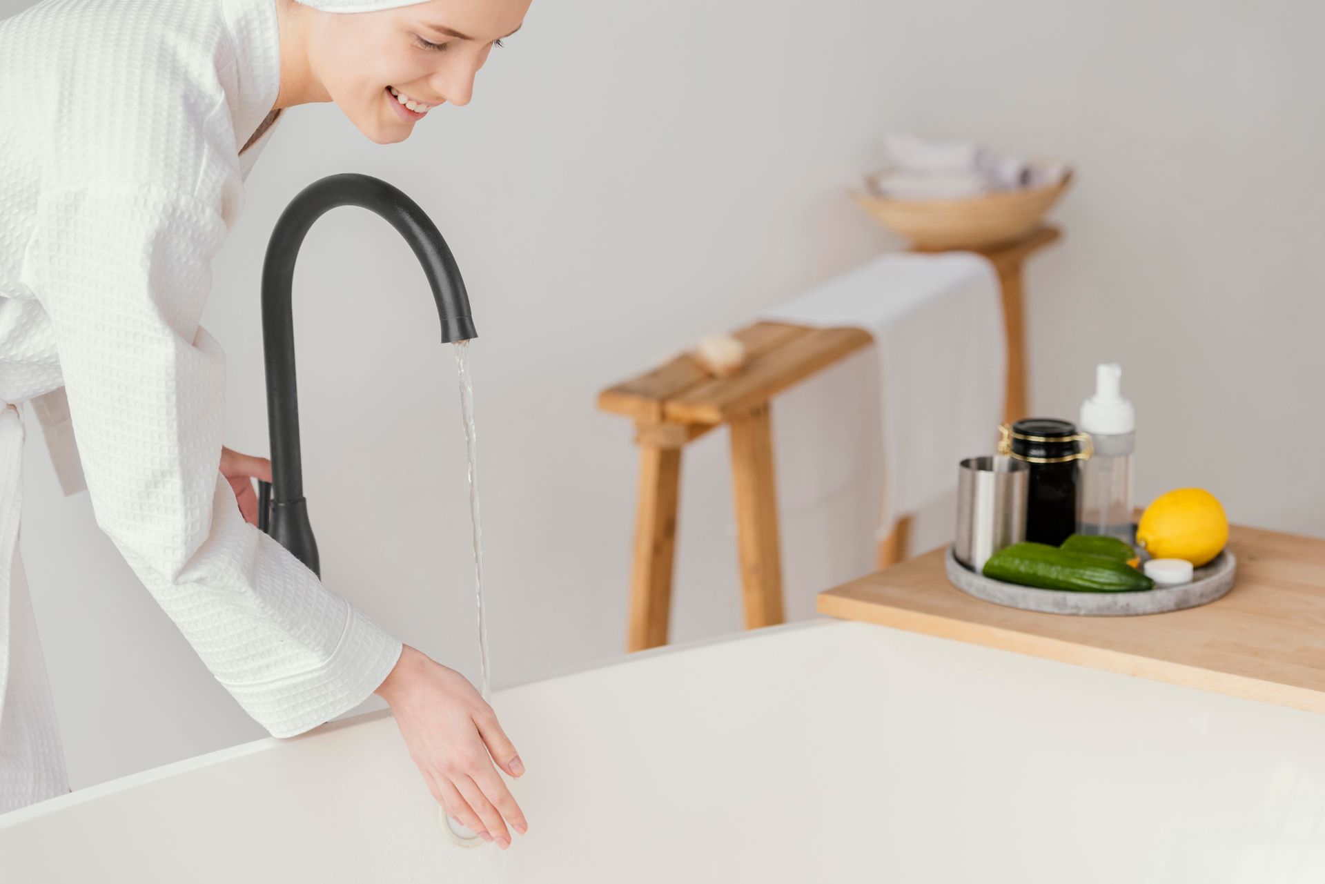 A woman is standing next to a bathtub in a bathroom.