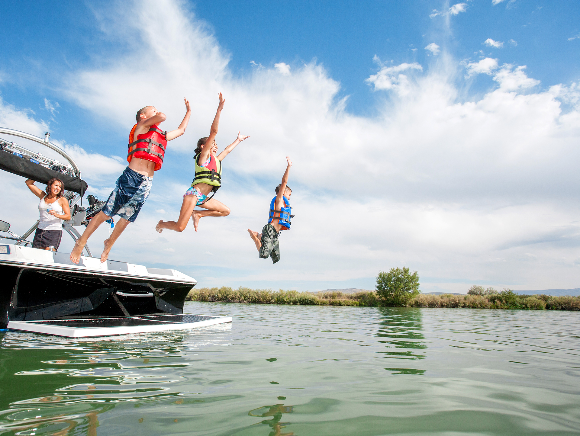 A group of people are jumping off a boat into the water
