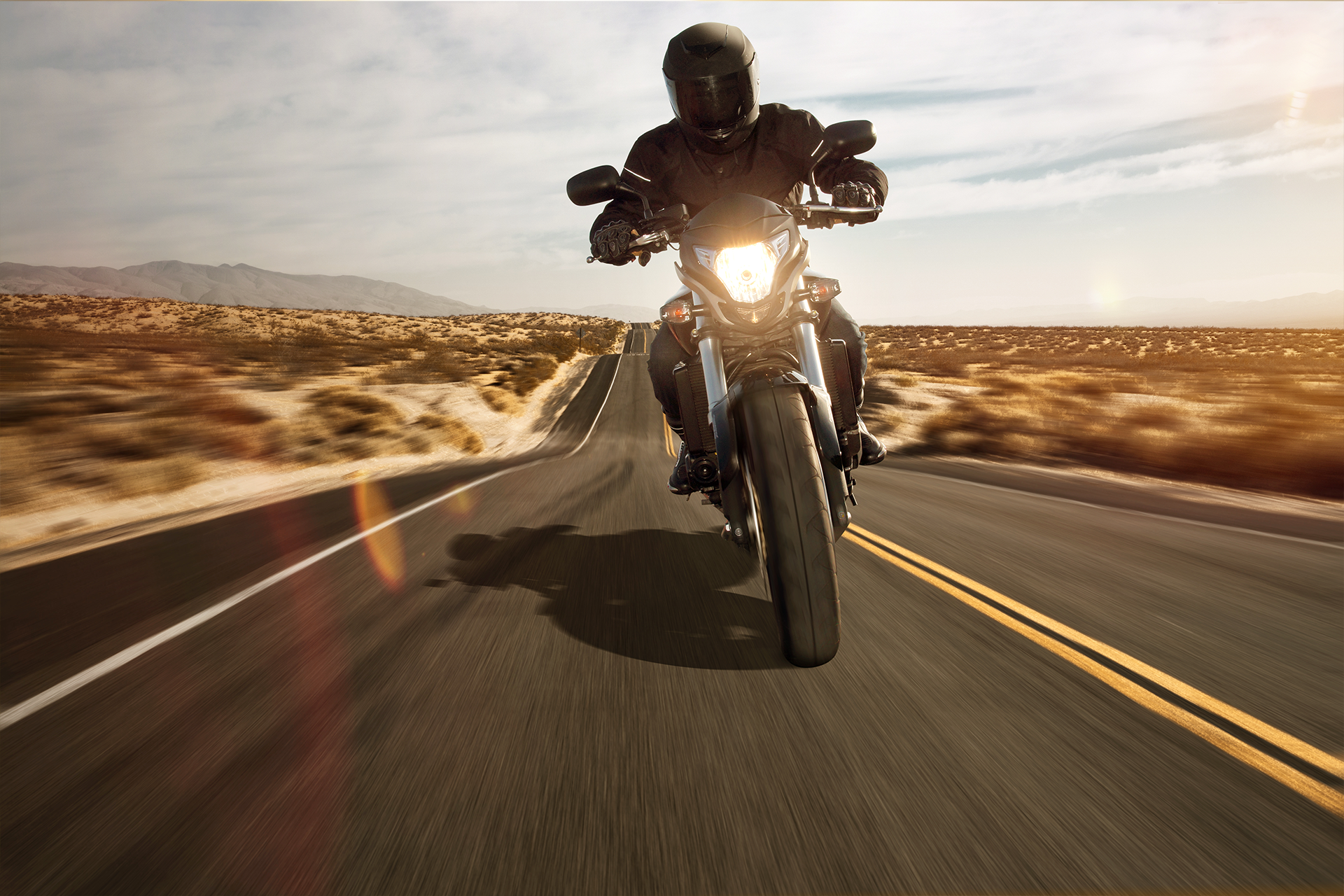 A man is riding a motorcycle down a desert road.