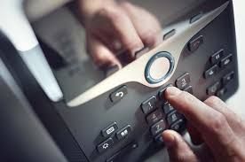 Hand dialing a black office phone.