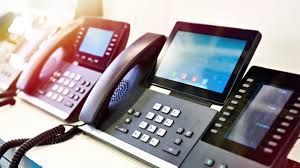 Several black VoIP desk phones with screens lined up.