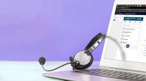 Headset rests on a laptop keyboard; screen shows a software interface.