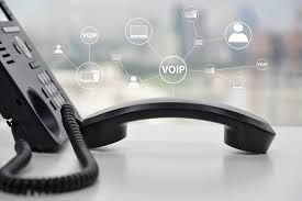 VoIP desk phone with handset off, connected to network diagram, on a desk.